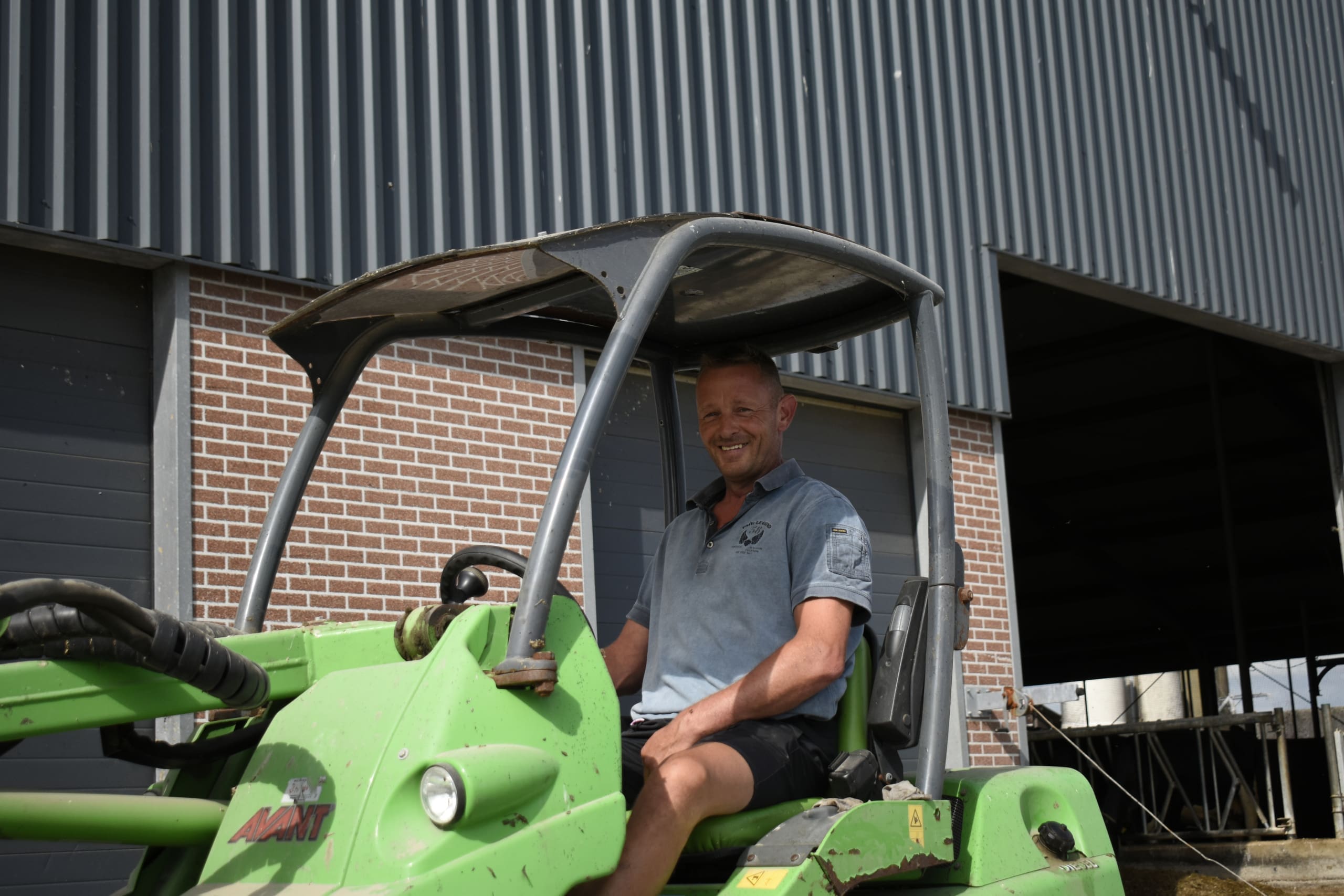 Melkveehouder Henk-Jan Breeuwsma op zijn shovel, klaar om de gescheiden mest uit de bunker te scheppen