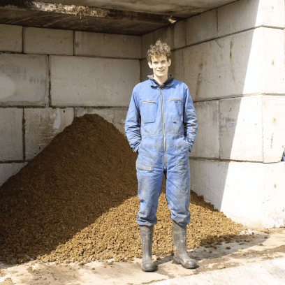Boerenzoon Piter Gerben Palma poseert tevreden voor een bult met gescheiden mest uit de mestscheider